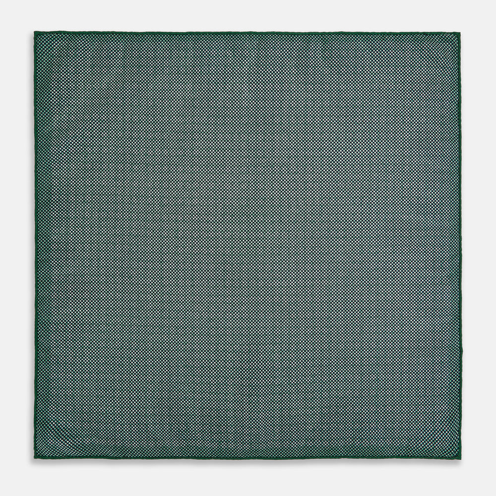 The Rosette Green Pocket Square in Silk by Turnbull & Asser UK features a small geometric medallion pattern and is shown folded to display a contrasting fine black-and-white design on the reverse side.