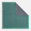 View 1 of product A square silk pocket square in Rosette Green by Turnbull & Asser UK, featuring a teal base with a grid of dark dots. One corner is folded to showcase the black and white microdot pattern on the reverse, while subtle hints of navy, aqua, and green form geometric medallions that lend a refined modern touch.