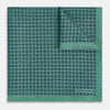 View 2 of product A square silk pocket square in Rosette Green by Turnbull & Asser UK, featuring a teal base with a grid of dark dots. One corner is folded to showcase the black and white microdot pattern on the reverse, while subtle hints of navy, aqua, and green form geometric medallions that lend a refined modern touch.