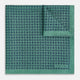 A square silk pocket square in Rosette Green by Turnbull & Asser UK, featuring a teal base with a grid of dark dots. One corner is folded to showcase the black and white microdot pattern on the reverse, while subtle hints of navy, aqua, and green form geometric medallions that lend a refined modern touch.