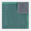 View 4 of product A square silk pocket square in Rosette Green by Turnbull & Asser UK, featuring a teal base with a grid of dark dots. One corner is folded to showcase the black and white microdot pattern on the reverse, while subtle hints of navy, aqua, and green form geometric medallions that lend a refined modern touch.