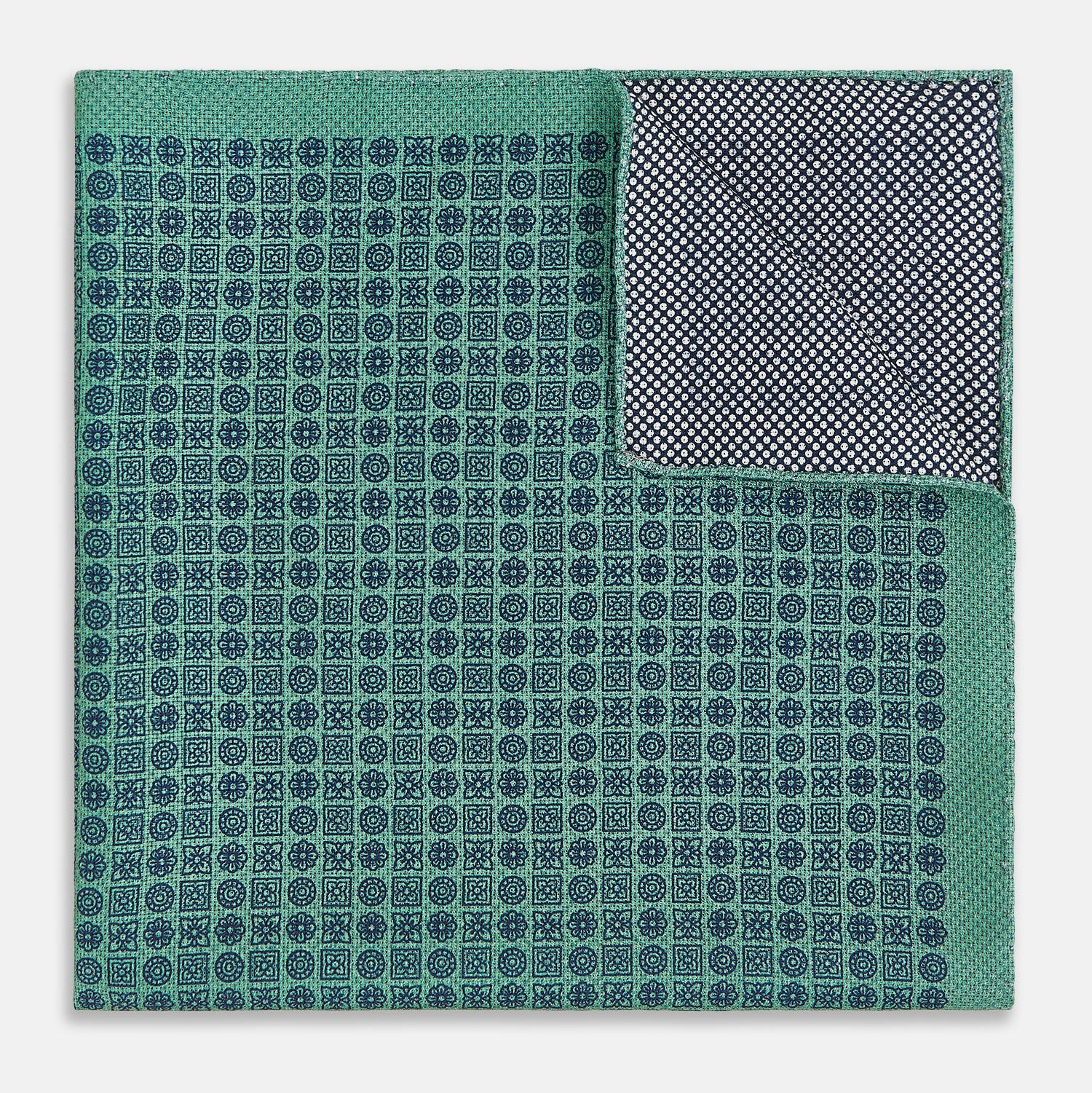 View 4 of product A square silk pocket square in Rosette Green by Turnbull & Asser UK, featuring a teal base with a grid of dark dots. One corner is folded to showcase the black and white microdot pattern on the reverse, while subtle hints of navy, aqua, and green form geometric medallions that lend a refined modern touch.