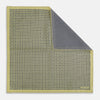 View 1 of product The Rosette Yellow Pocket Square in Silk by Turnbull & Asser UK features a square design with a yellow border, adorned with a grid of small black and white circles. One corner is neatly folded to reveal a reverse side in a refined black and white micro-checkered pattern, while subtle geometric medallions lend an added touch of elegance to the overall look.