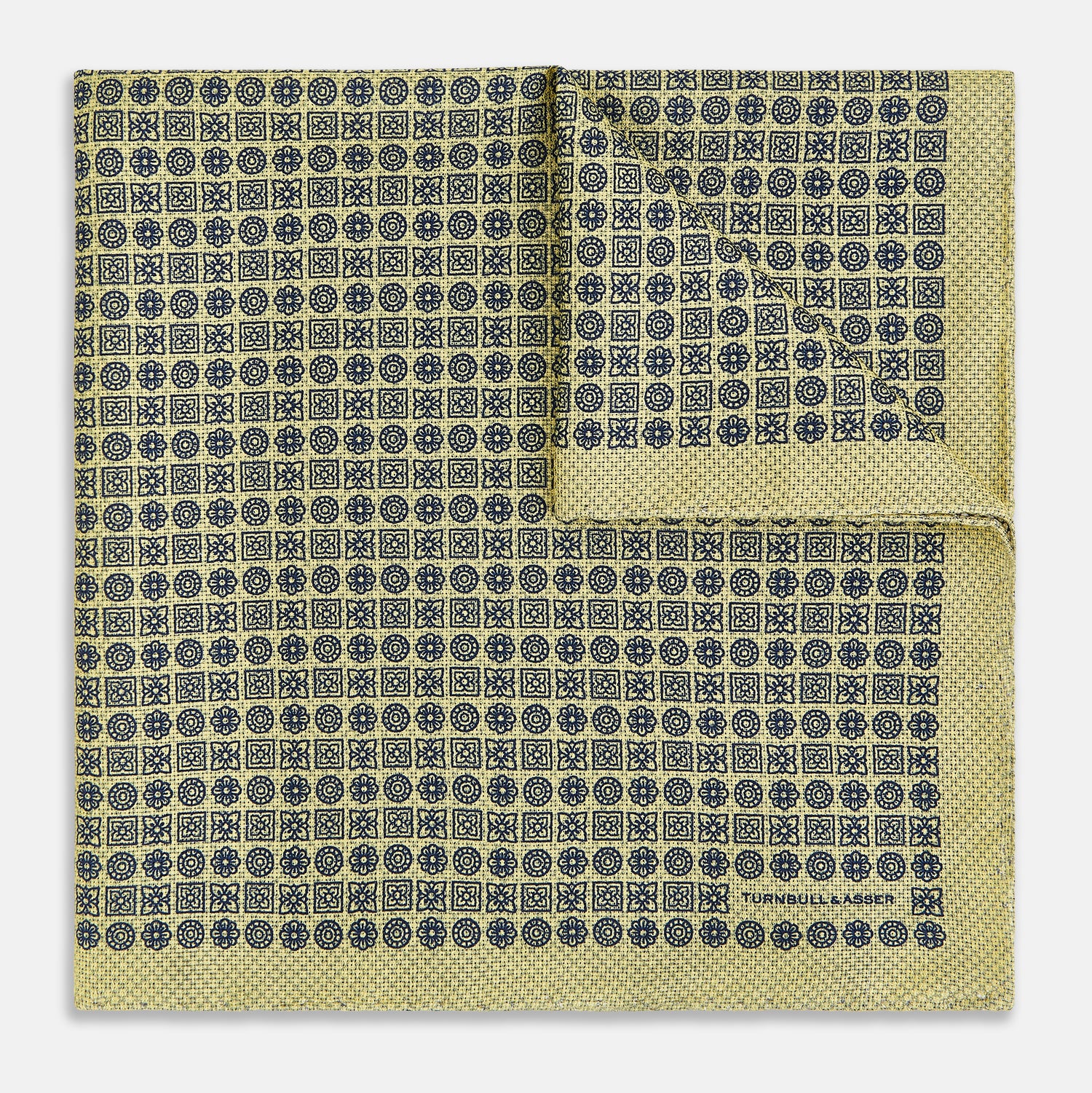 View 2 of product The Rosette Yellow Pocket Square in Silk by Turnbull & Asser UK features a square design with a yellow border, adorned with a grid of small black and white circles. One corner is neatly folded to reveal a reverse side in a refined black and white micro-checkered pattern, while subtle geometric medallions lend an added touch of elegance to the overall look.