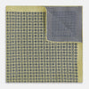 View 4 of product The Rosette Yellow Pocket Square in Silk by Turnbull & Asser UK features a square design with a yellow border, adorned with a grid of small black and white circles. One corner is neatly folded to reveal a reverse side in a refined black and white micro-checkered pattern, while subtle geometric medallions lend an added touch of elegance to the overall look.
