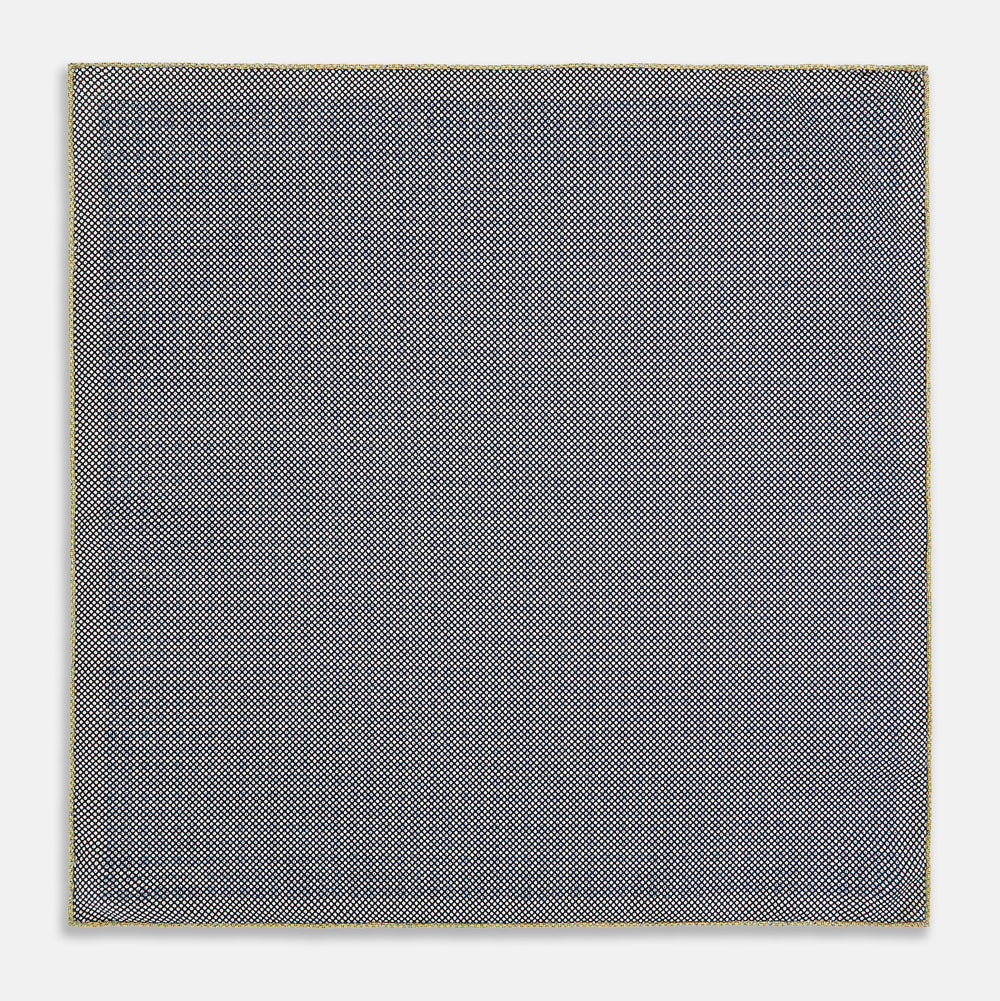 The Rosette Yellow Pocket Square in Silk by Turnbull & Asser UK features a square design with a yellow border, adorned with a grid of small black and white circles. One corner is neatly folded to reveal a reverse side in a refined black and white micro-checkered pattern, while subtle geometric medallions lend an added touch of elegance to the overall look.