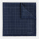 The Checked Blue Pocket Square in Silk by Turnbull & Asser UK features a navy base with a light blue grid pattern on one side and a refined dotted design on the other. This double-sided accessory is shown partially folded to elegantly showcase both distinctive patterns.