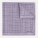 The Checked Lilac Pocket Square in Silk by Turnbull & Asser UK features a grid pattern in purple with a solid border, neatly folded to display its double-sided design and contrasting black and white dotted squares on the reverse side.