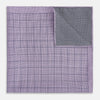 View 4 of product The Checked Lilac Pocket Square in Silk by Turnbull & Asser UK features a grid pattern in purple with a solid border, neatly folded to display its double-sided design and contrasting black and white dotted squares on the reverse side.