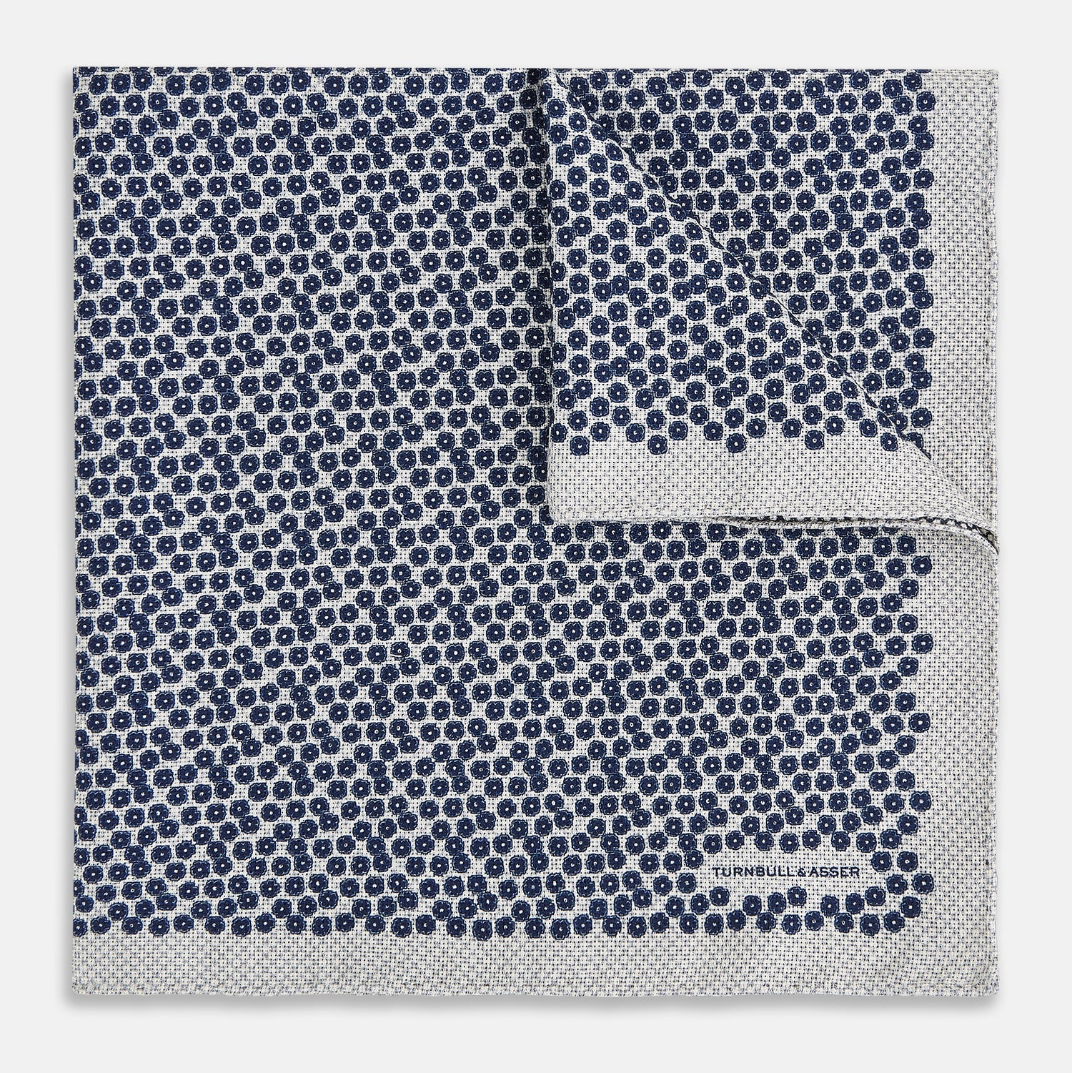View 2 of product A square silk pocket square from Turnbull & Asser UK, featuring a subtle floral grey pattern; one corner is folded to reveal its double-sided design with a complementary pattern on the reverse side.