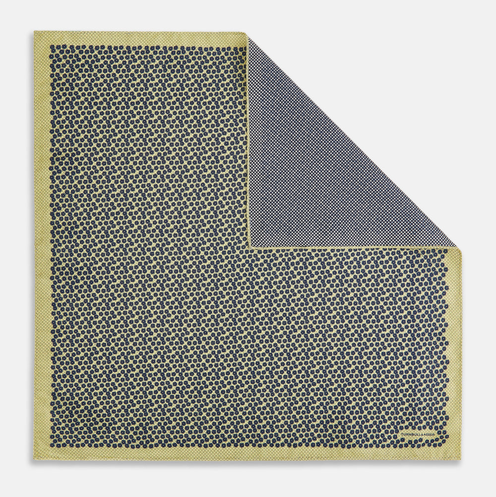 Introducing the Floral Yellow Pocket Square in Silk by Turnbull & Asser UK—a sophisticated square accessory featuring a vibrant yellow border and a black-and-white geometric dot pattern. One corner is tastefully folded to reveal its double-sided design, showcasing a smaller, denser dot motif on the reverse. Perfect for adding a modern touch of flair to any outfit or setting.