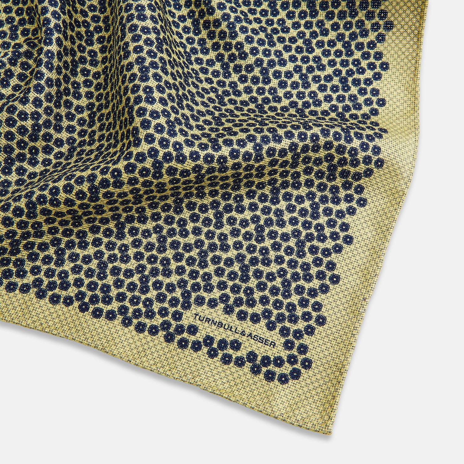 View 3 of product Introducing the Floral Yellow Pocket Square in Silk by Turnbull & Asser UK—a sophisticated square accessory featuring a vibrant yellow border and a black-and-white geometric dot pattern. One corner is tastefully folded to reveal its double-sided design, showcasing a smaller, denser dot motif on the reverse. Perfect for adding a modern touch of flair to any outfit or setting.