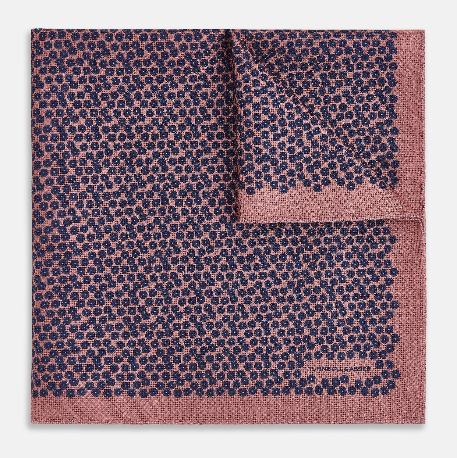 View 2 of product The Floral Pink Pocket Square in Silk by Turnbull & Asser UK showcases a refined pattern with a pink floral design and a contrasting border. The top right corner is elegantly folded to reveal the reverse side’s complementary blue and white dotted motif, emphasizing its double-sided versatility.