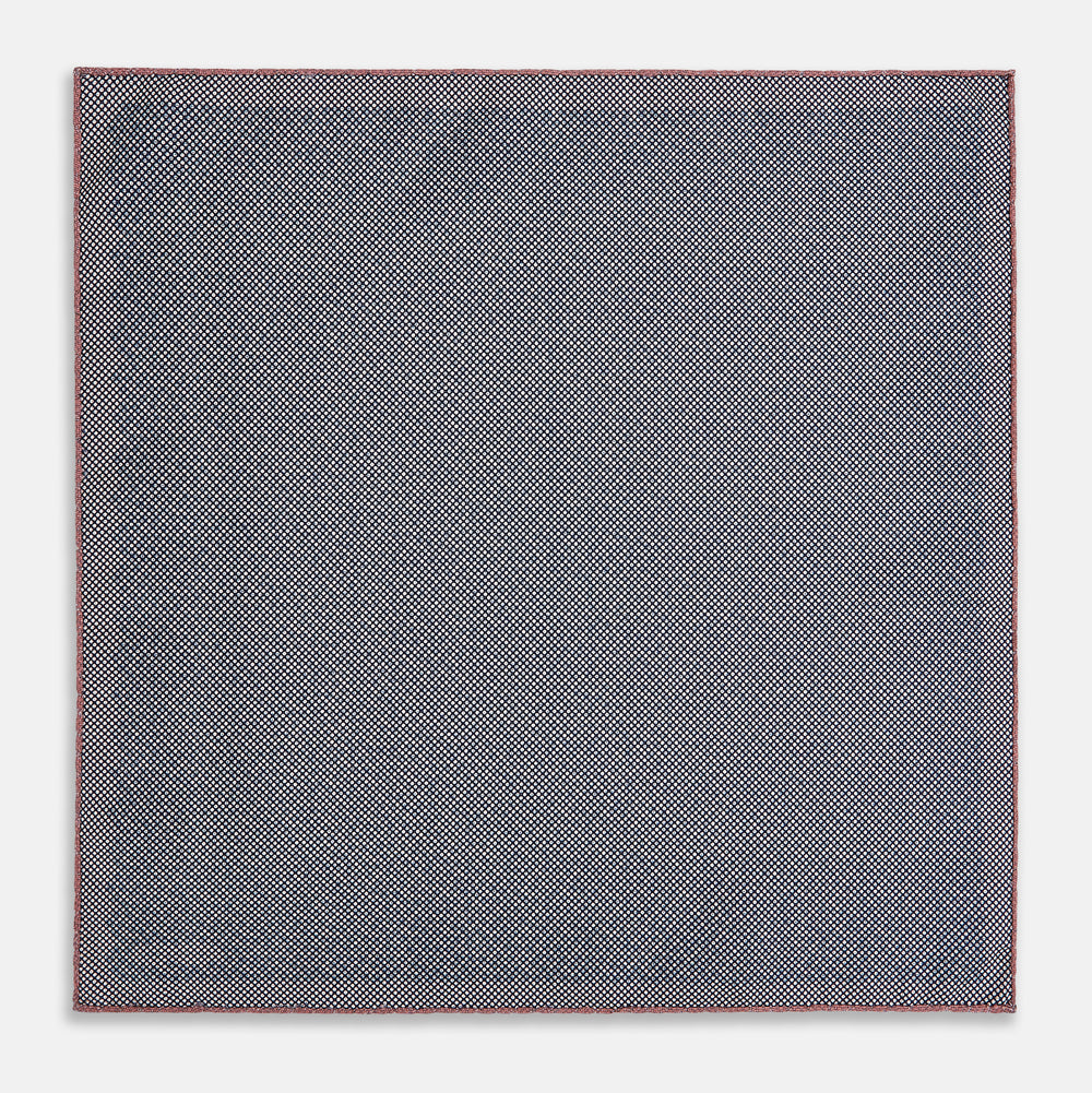 The Floral Pink Pocket Square in Silk by Turnbull & Asser UK showcases a refined pattern with a pink floral design and a contrasting border. The top right corner is elegantly folded to reveal the reverse side’s complementary blue and white dotted motif, emphasizing its double-sided versatility.