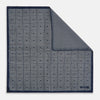 View 1 of product Introducing the Geometric Navy Tile Pocket Square in Silk by Turnbull & Asser UK—a folded navy and white accessory showcasing a double-sided design, with one side featuring concentric squares that form a striking geometric pattern and the other adorned with an elegant small dot motif.