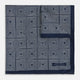 Introducing the Geometric Navy Tile Pocket Square in Silk by Turnbull & Asser UK—a folded navy and white accessory showcasing a double-sided design, with one side featuring concentric squares that form a striking geometric pattern and the other adorned with an elegant small dot motif.