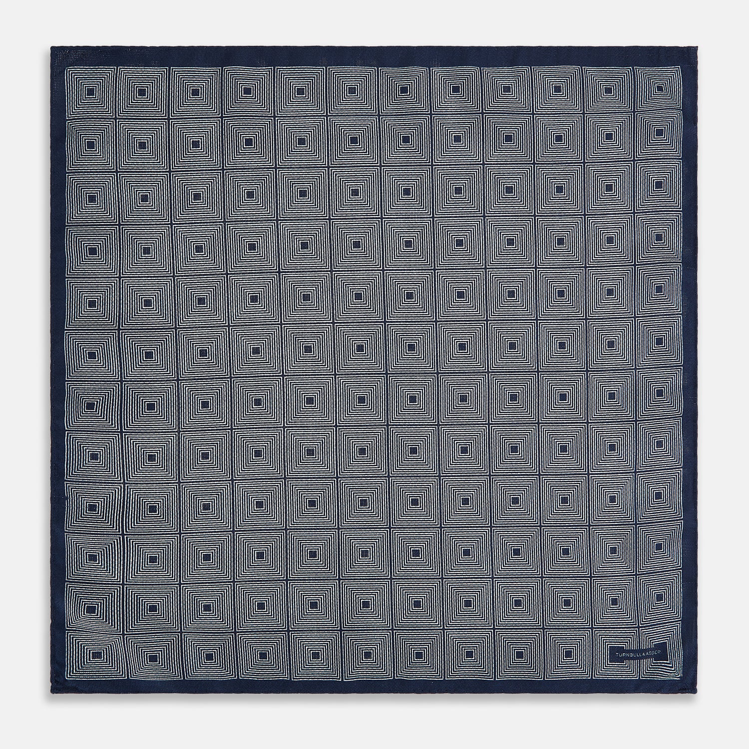 View 5 of product Introducing the Geometric Navy Tile Pocket Square in Silk by Turnbull & Asser UK—a folded navy and white accessory showcasing a double-sided design, with one side featuring concentric squares that form a striking geometric pattern and the other adorned with an elegant small dot motif.