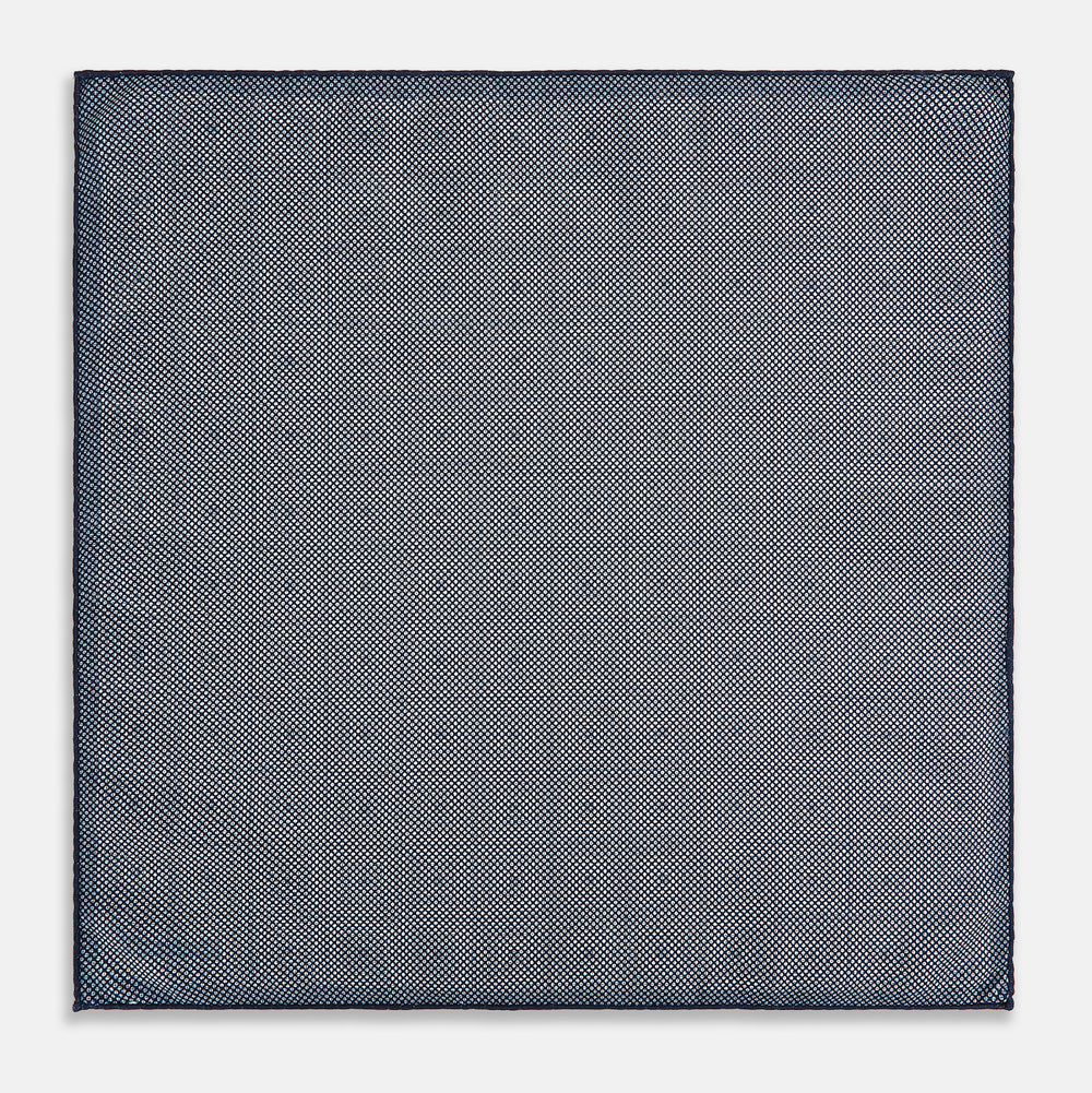 Introducing the Geometric Navy Tile Pocket Square in Silk by Turnbull & Asser UK—a folded navy and white accessory showcasing a double-sided design, with one side featuring concentric squares that form a striking geometric pattern and the other adorned with an elegant small dot motif.