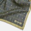 View 3 of product The Turnbull & Asser UK Geometric Yellow Tile Pocket Square in Silk features a sophisticated geometric square pattern in gold and navy, accented with subtle concentric squares and a discreet label stitched into the bottom right corner. Its double-sided design is highlighted by a folded corner that reveals a contrasting dotted navy and white underside.