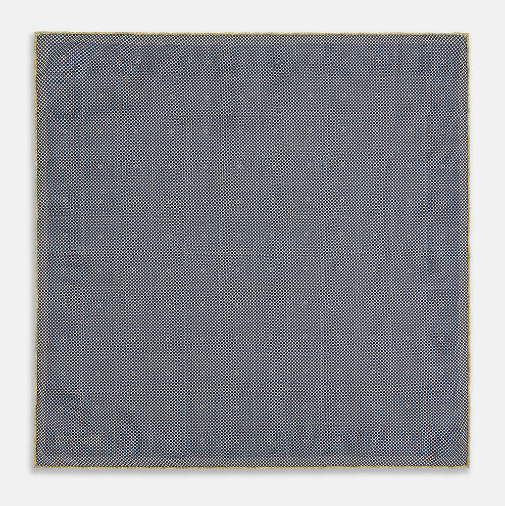 The Turnbull & Asser UK Geometric Yellow Tile Pocket Square in Silk features a sophisticated geometric square pattern in gold and navy, accented with subtle concentric squares and a discreet label stitched into the bottom right corner. Its double-sided design is highlighted by a folded corner that reveals a contrasting dotted navy and white underside.