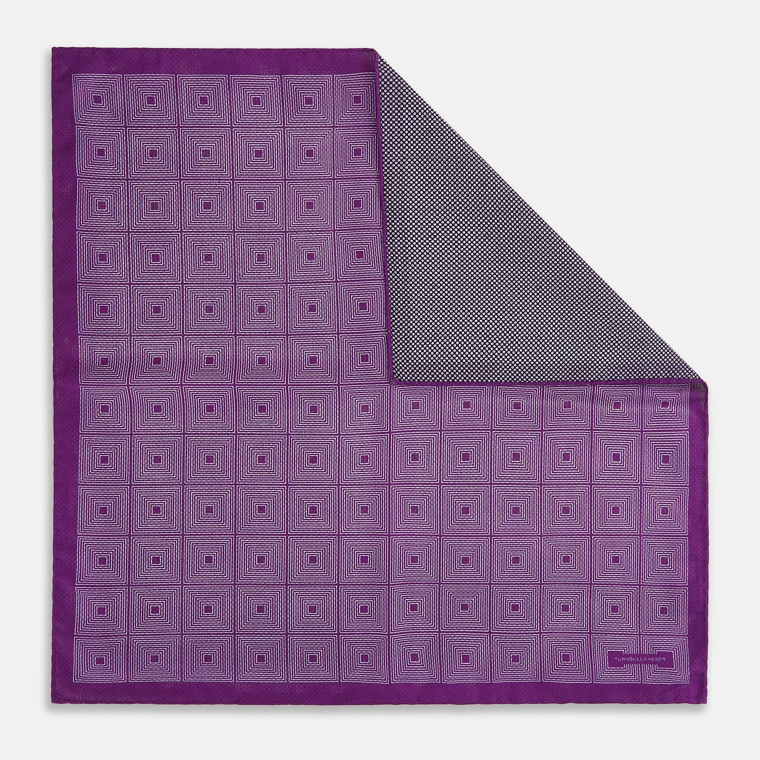 View 1 of product The Turnbull & Asser UK Geometric Purple Tile Pocket Square in Silk features a vibrant purple hue adorned with concentric square motifs. One corner is folded to reveal its double-sided design, showcasing a contrasting black-and-white dotted underside.