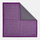 The Turnbull & Asser UK Geometric Purple Tile Pocket Square in Silk features a vibrant purple hue adorned with concentric square motifs. One corner is folded to reveal its double-sided design, showcasing a contrasting black-and-white dotted underside.