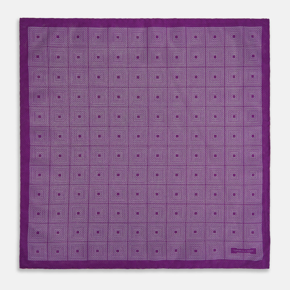The Turnbull & Asser UK Geometric Purple Tile Pocket Square in Silk features a vibrant purple hue adorned with concentric square motifs. One corner is folded to reveal its double-sided design, showcasing a contrasting black-and-white dotted underside.