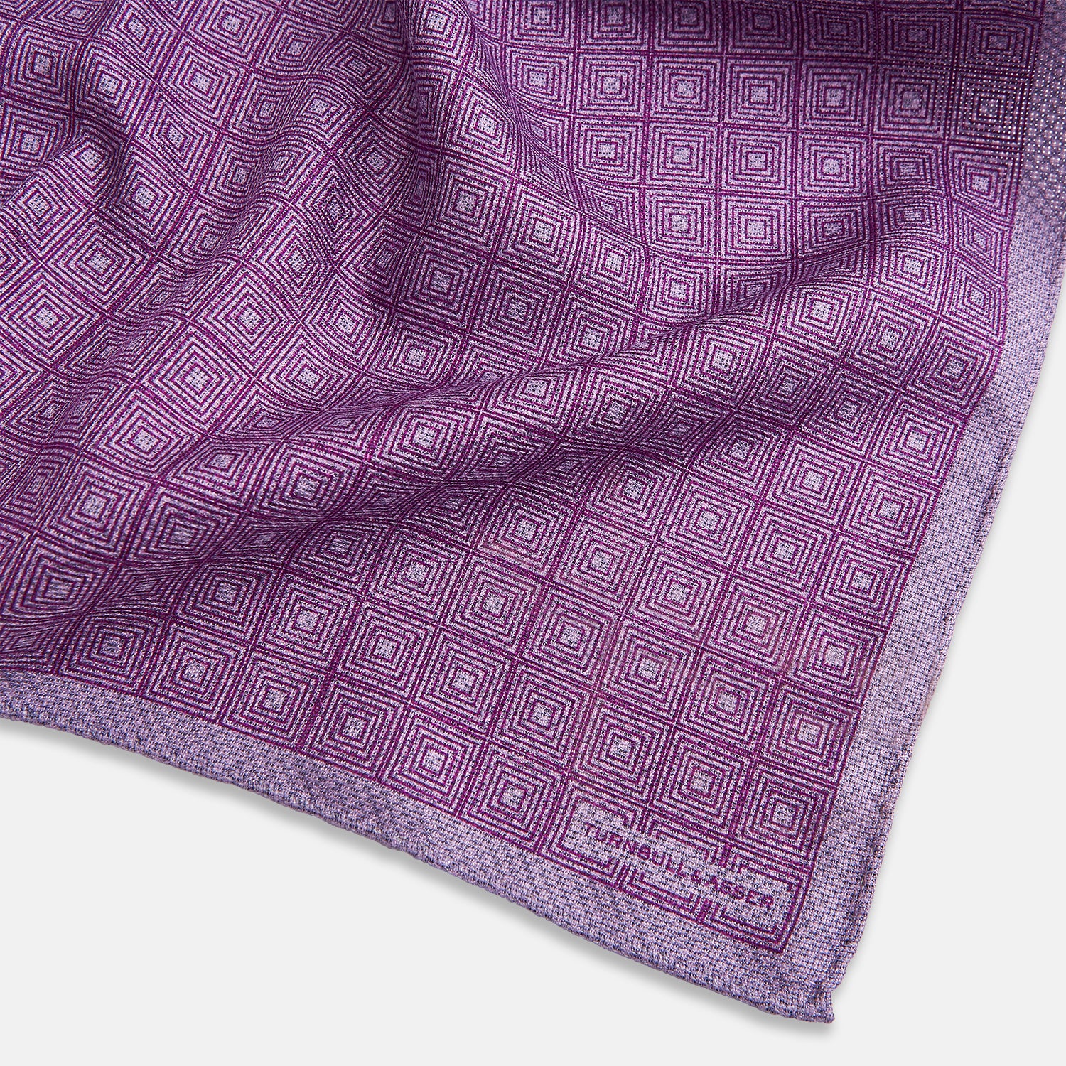 View 3 of product Certainly! Here’s a rewritten version of your sentence, incorporating the product data: The Geometric Lilac Tile Pocket Square in Silk by Turnbull & Asser UK features a lilac purple geometric pattern with a subtle square design, partially folded to reveal its double-sided construction with a contrasting black and white dotted pattern on the reverse.