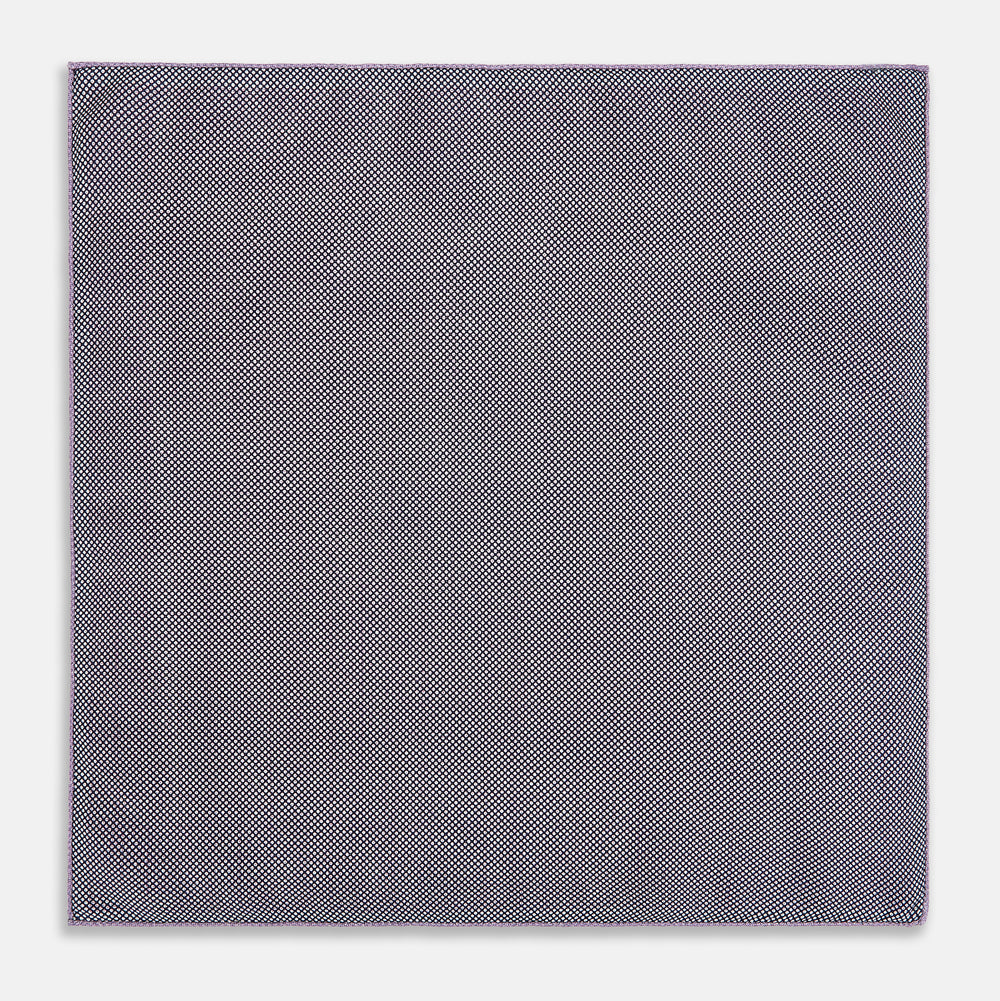 Certainly! Here’s a rewritten version of your sentence, incorporating the product data: The Geometric Lilac Tile Pocket Square in Silk by Turnbull & Asser UK features a lilac purple geometric pattern with a subtle square design, partially folded to reveal its double-sided construction with a contrasting black and white dotted pattern on the reverse.