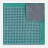 View 4 of product A geometric green silk pocket square by Turnbull & Asser UK, featuring a subtle houndstooth weave with a teal border, and partially folded to reveal a contrasting black and white micro-dot reverse pattern.