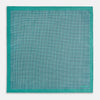 View 5 of product A geometric green silk pocket square by Turnbull & Asser UK, featuring a subtle houndstooth weave with a teal border, and partially folded to reveal a contrasting black and white micro-dot reverse pattern.