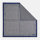 The Geometric Blue Pocket Square in Silk from Turnbull & Asser UK showcases a blue border and double-sided design, with a geometric pattern at the center. A folded corner reveals a refined, tighter dot motif on the reverse side, emphasizing the intricate craftsmanship of this finely woven accessory.