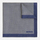 The Geometric Blue Pocket Square in Silk from Turnbull & Asser UK showcases a blue border and double-sided design, with a geometric pattern at the center. A folded corner reveals a refined, tighter dot motif on the reverse side, emphasizing the intricate craftsmanship of this finely woven accessory.