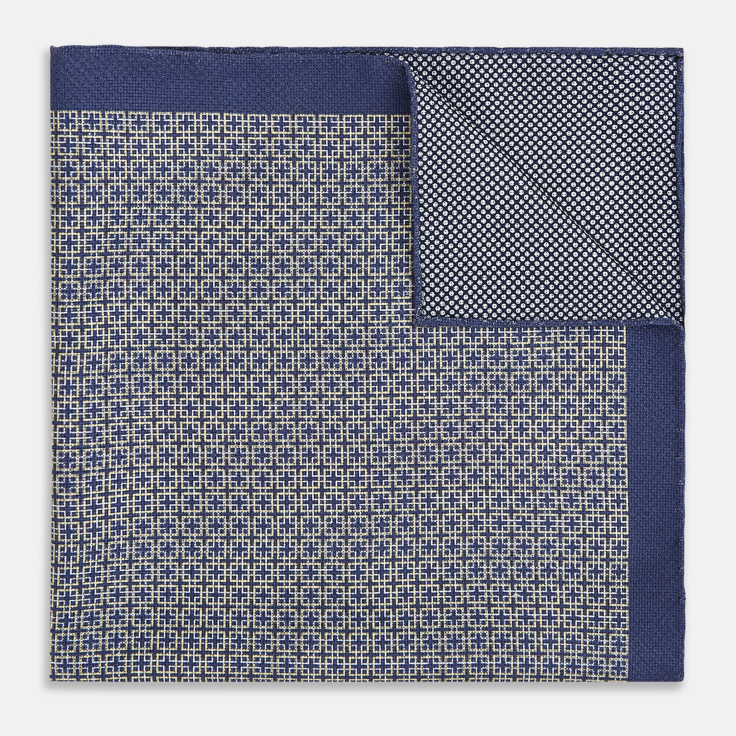 View 4 of product The Geometric Blue Pocket Square in Silk from Turnbull & Asser UK showcases a blue border and double-sided design, with a geometric pattern at the center. A folded corner reveals a refined, tighter dot motif on the reverse side, emphasizing the intricate craftsmanship of this finely woven accessory.
