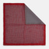 View 1 of product Turnbull & Asser UK’s Geometric Red Pocket Square in Silk features a small white checkered pattern and a cleverly flipped corner to showcase its contrasting black and white micro-dot reverse design.