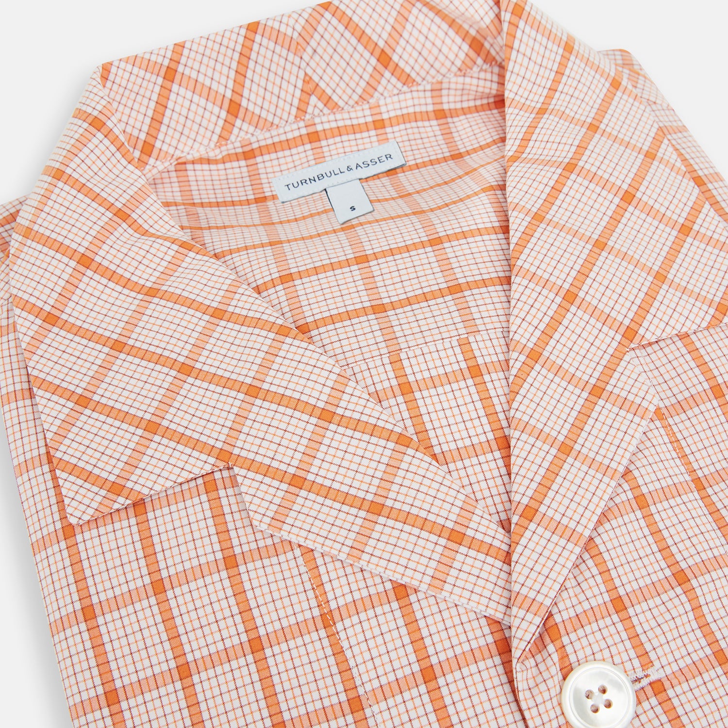 View 2 of product The Orange Graph Overlay Check Pyjama Shirt by Turnbull & Asser features long sleeves, a notched collar, and a front chest pocket, shown here laid flat on a white background.