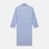 View 4 of product The Turnbull & Asser Light Blue Piped End-On-End Cotton Gown features a belted waist, three front pockets, and red piping on the collar, pockets, and cuffs—ideal for travel. Displayed against a white background.