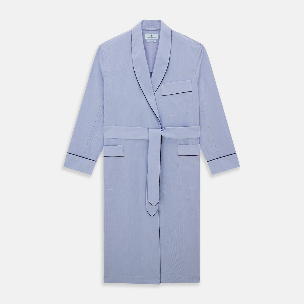 The Blue Fine Bengal Stripe Piped Cotton Gown by Turnbull & Asser features long sleeves, a shawl collar, navy piping, three pockets, and a fabric belt—ideal for those who appreciate classic cotton dressing gowns.