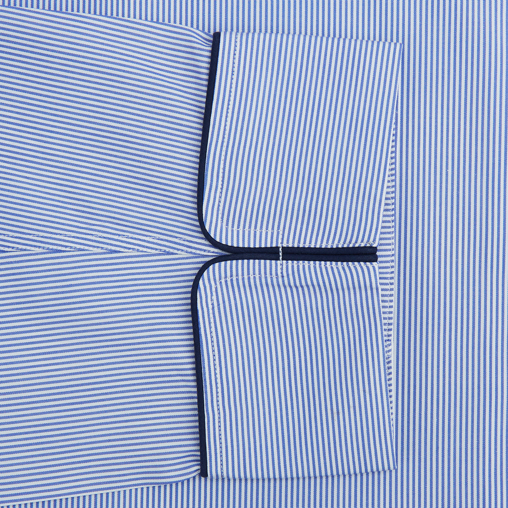 The Blue Fine Bengal Stripe Piped Cotton Gown by Turnbull & Asser features long sleeves, a shawl collar, navy piping, three pockets, and a fabric belt—ideal for those who appreciate classic cotton dressing gowns.