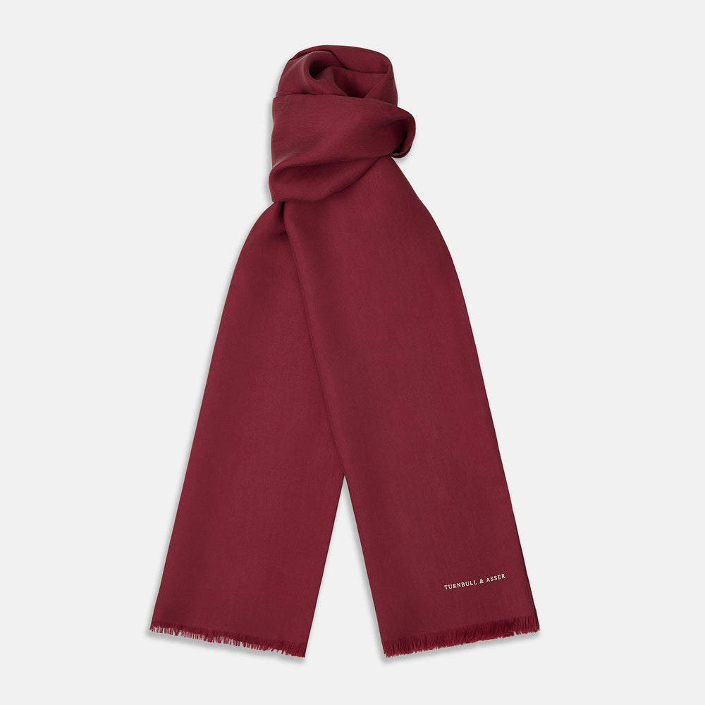 The Plain Wine Silk Scarf by Turnbull & Asser is a long, smooth accessory with subtle fringe and white Turnbull & Asser embroidery on one corner. It comes neatly folded in a deep wine color, perfect for an elegant touch.