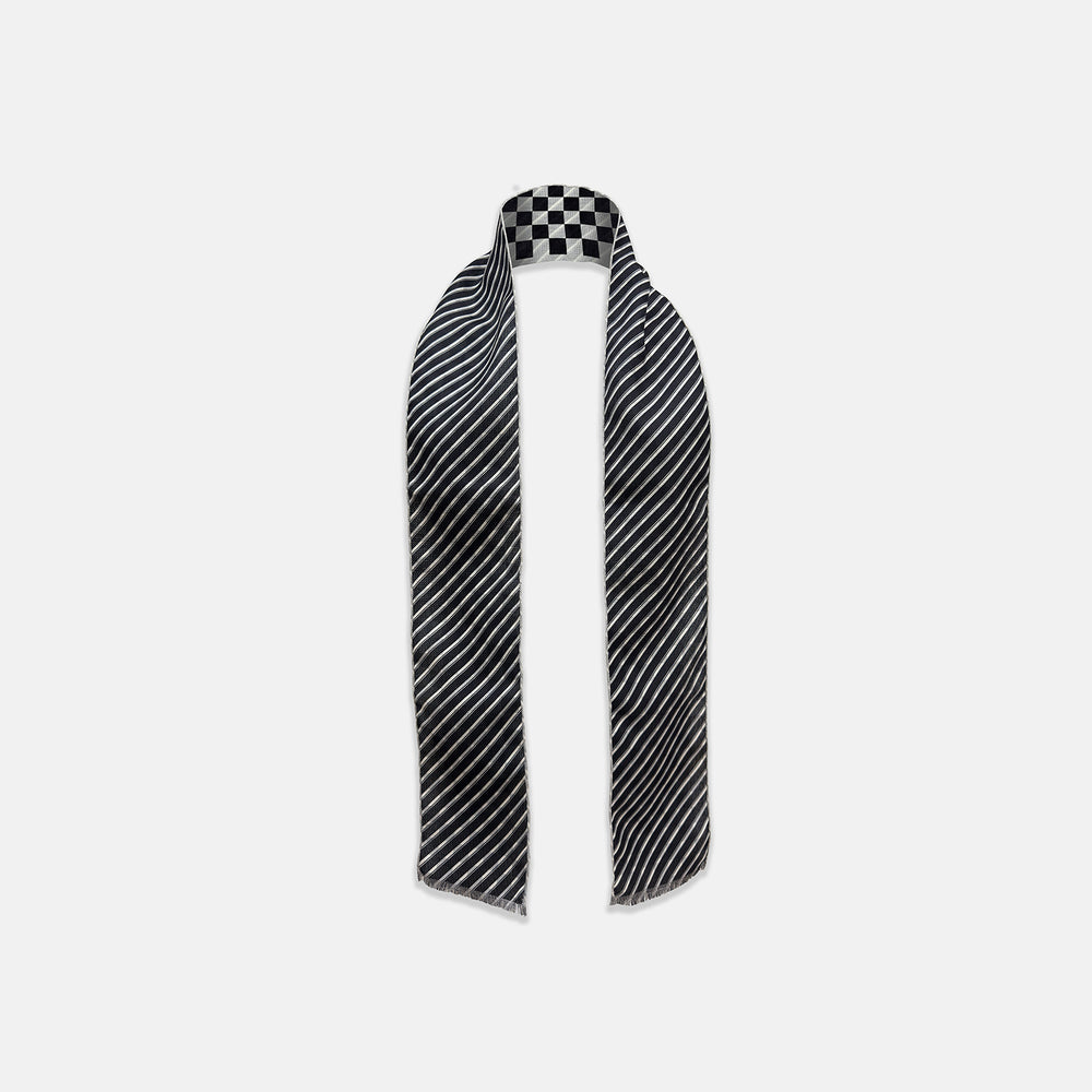 The Chequered Navy on White Frame Small Scarf in Silk by Turnbull & Asser UK is a long silk accessory featuring a classic black and white checkerboard pattern laid flat against a white background. Its ends are finished with a thin, fringed border, while the top edge is accented by diagonal stripes. The double-sided chequered design adds a stylish twist, with touches of navy and subtle hints of white bringing sophisticated detail to this timeless look.