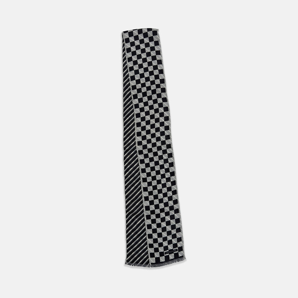 The Chequered Navy on White Frame Small Scarf in Silk by Turnbull & Asser UK is a long silk accessory featuring a classic black and white checkerboard pattern laid flat against a white background. Its ends are finished with a thin, fringed border, while the top edge is accented by diagonal stripes. The double-sided chequered design adds a stylish twist, with touches of navy and subtle hints of white bringing sophisticated detail to this timeless look.