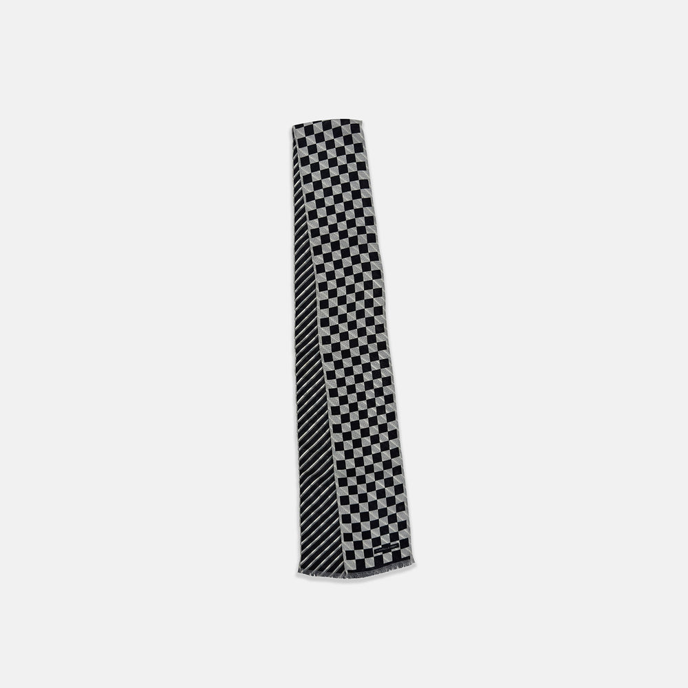 The Chequered Navy on White Frame Small Scarf in Silk by Turnbull & Asser UK is a long silk accessory featuring a classic black and white checkerboard pattern laid flat against a white background. Its ends are finished with a thin, fringed border, while the top edge is accented by diagonal stripes. The double-sided chequered design adds a stylish twist, with touches of navy and subtle hints of white bringing sophisticated detail to this timeless look.