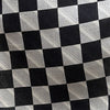 View 4 of product The Chequered Navy on White Frame Small Scarf in Silk by Turnbull & Asser UK is a long silk accessory featuring a classic black and white checkerboard pattern laid flat against a white background. Its ends are finished with a thin, fringed border, while the top edge is accented by diagonal stripes. The double-sided chequered design adds a stylish twist, with touches of navy and subtle hints of white bringing sophisticated detail to this timeless look.