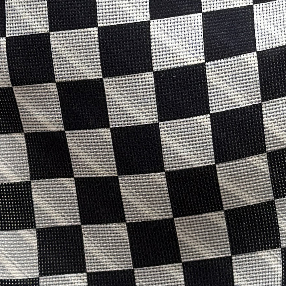 The Chequered Navy on White Frame Small Scarf in Silk by Turnbull & Asser UK is a long silk accessory featuring a classic black and white checkerboard pattern laid flat against a white background. Its ends are finished with a thin, fringed border, while the top edge is accented by diagonal stripes. The double-sided chequered design adds a stylish twist, with touches of navy and subtle hints of white bringing sophisticated detail to this timeless look.