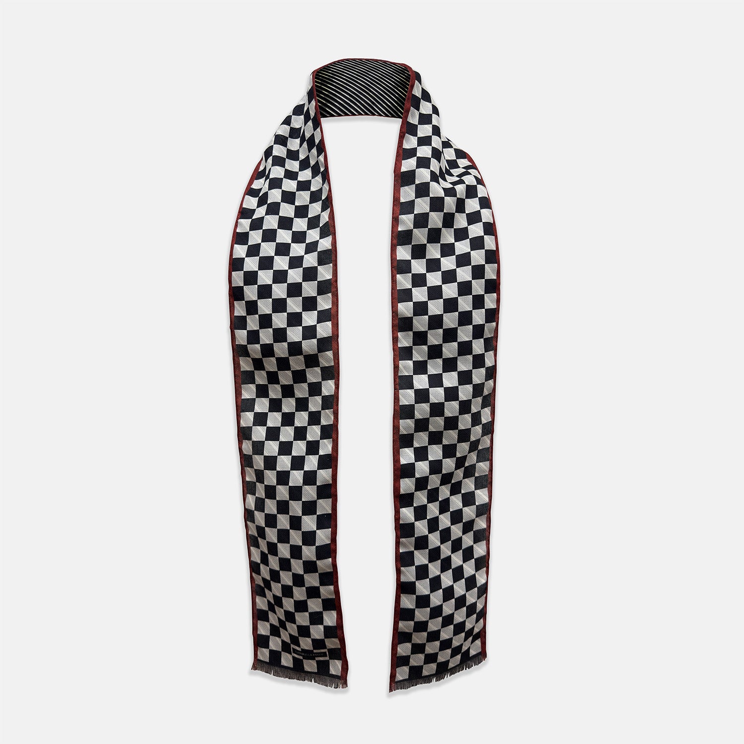 View 1 of product Introducing the Chequered Navy on Red Frame Small Scarf in Silk by Turnbull & Asser UK—a luxurious silk accessory featuring a navy and white chequered pattern, accented with thin red borders and delicate fringe at each end. Displayed against a white background, this scarf pays homage to British motoring heritage and the enduring elegance of Concours style.