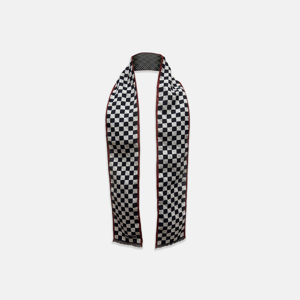 Introducing the Chequered Navy on Red Frame Small Scarf in Silk by Turnbull & Asser UK—a luxurious silk accessory featuring a navy and white chequered pattern, accented with thin red borders and delicate fringe at each end. Displayed against a white background, this scarf pays homage to British motoring heritage and the enduring elegance of Concours style.