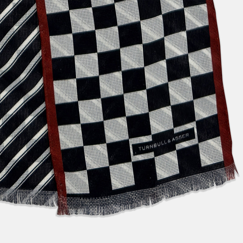 Introducing the Chequered Navy on Red Frame Small Scarf in Silk by Turnbull & Asser UK—a luxurious silk accessory featuring a navy and white chequered pattern, accented with thin red borders and delicate fringe at each end. Displayed against a white background, this scarf pays homage to British motoring heritage and the enduring elegance of Concours style.