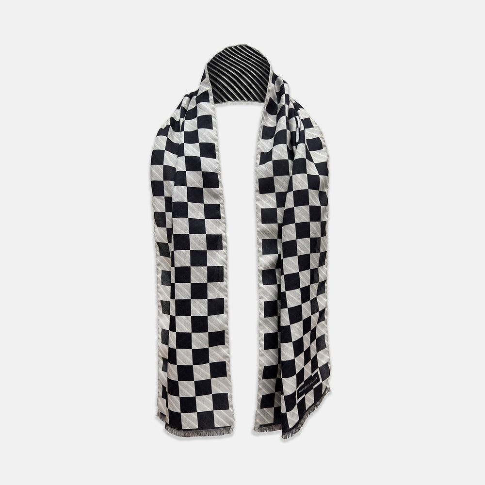 A Chequered Navy on White Frame Large Scarf in Silk from Turnbull & Asser UK, featuring a striking navy and white checkerboard motif inspired by classic British motoring heritage, is gracefully displayed over an invisible stand with its ends cascading downward and the top artfully folded into a striped semicircle—an impeccable choice for making a stylish statement at the Concours of Elegance 2026.