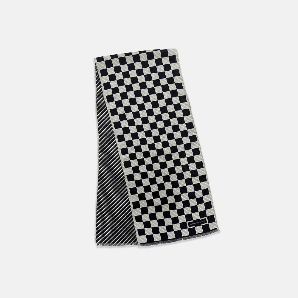 A Chequered Navy on White Frame Large Scarf in Silk from Turnbull & Asser UK, featuring a striking navy and white checkerboard motif inspired by classic British motoring heritage, is gracefully displayed over an invisible stand with its ends cascading downward and the top artfully folded into a striped semicircle—an impeccable choice for making a stylish statement at the Concours of Elegance 2026.